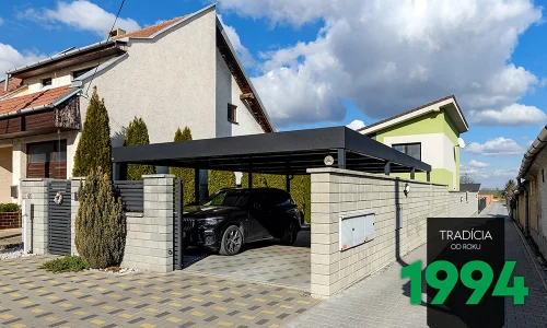 Autó a kocsibeálló alatt a betonkerítés mellett