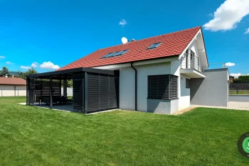Fehete pergola egy fehér családi ház mellett
