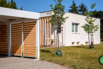 Gardeon kétállásos kocsibeálló fehér tetővel a fák között a kertben