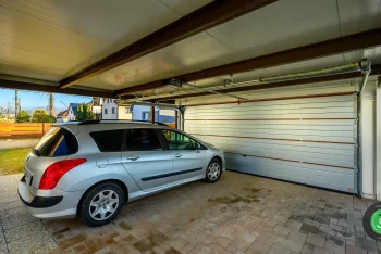 Parkoló autó a garázskapuval ellátott GARDEON kocsibeálló alatt