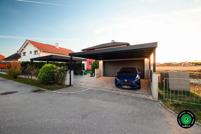 Modern garázs előtetővel rendezett előkerttel és bokrokkal