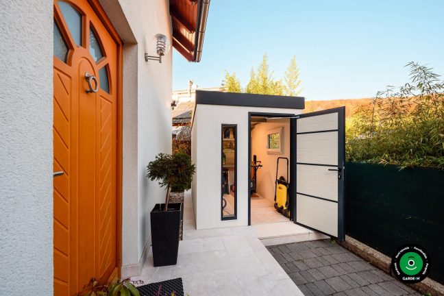 Kerti házikó a ház mellett nyitott ajtókkal és felszereléssel