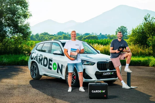 Két GARDEON ügynök mintakönyvvel és tablettel a cég BMW-jénél.