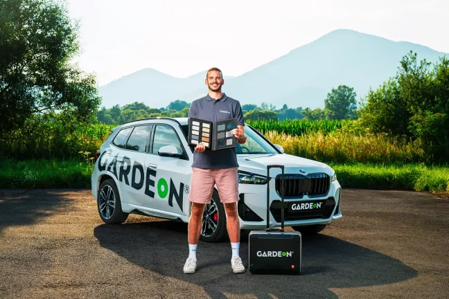GARDEON ügynök színmintakönyvet tart a cég BMW-je előtt.
