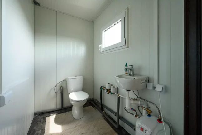 Fürdőszoba WC-vel, mosdóval és az ablak mellett elhelyezett vízmelegítővel