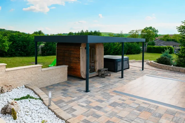 Antracit színű pergola a medencénél átlátszó fedéllel, fehér kaviccsal és burkolt területtel körülötte