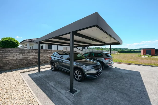 A kocsibeálló antracit lapostetője védi a két SUV-t a családi ház mellett.
