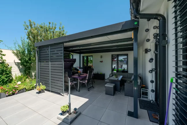 Étkezőasztal és hintaszék a pergola alatt grillel
