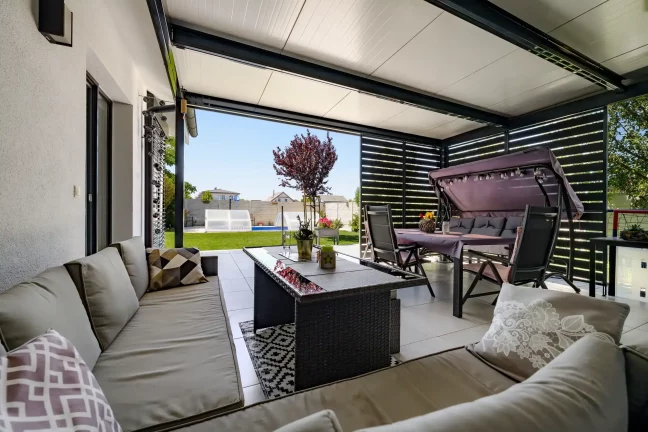 Kilátás a pergola alól a kertre, fával és medencével