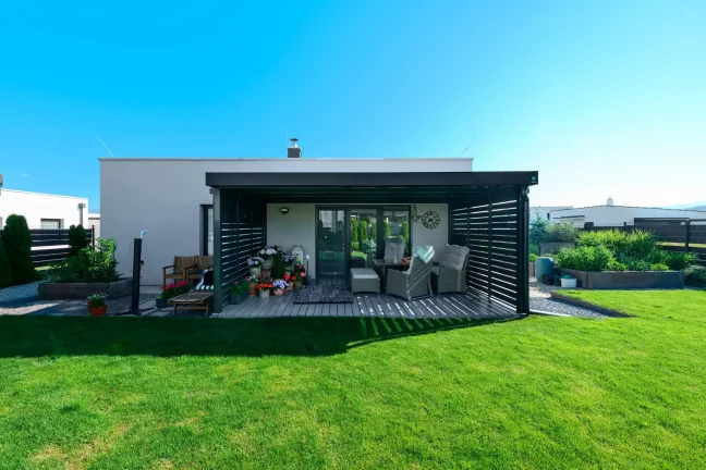 Antracit pergola fémbetétekkel családi ház füves kertjénél.