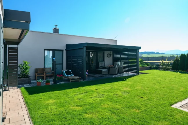 Antracit pergola fémbetétekkel kertes családi háznál.