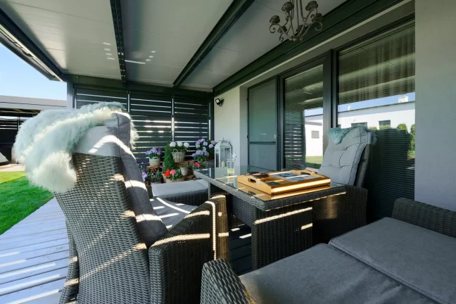 Antracit pergola belseje fémbetétekkel és kerti bútorokkal.