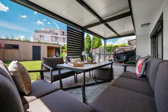 Egy pergola belső tere luxus kerti bútorokkal, kilátással a kertre